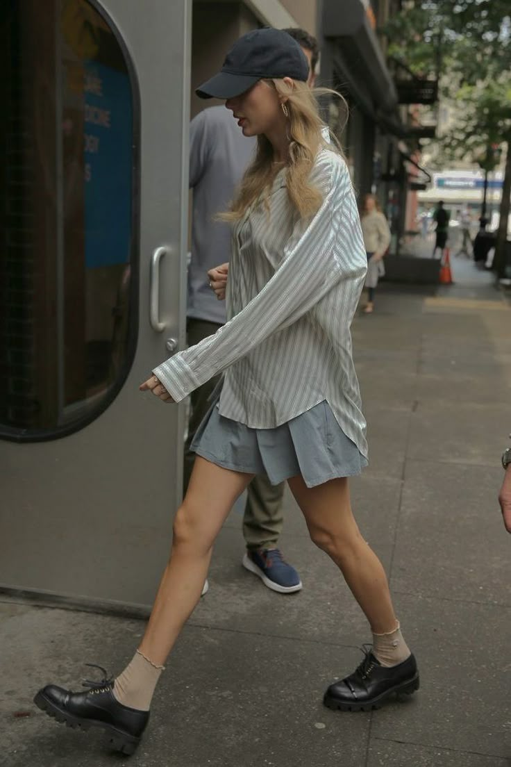 a woman walking down the street in short shorts and a baseball cap with her leg up