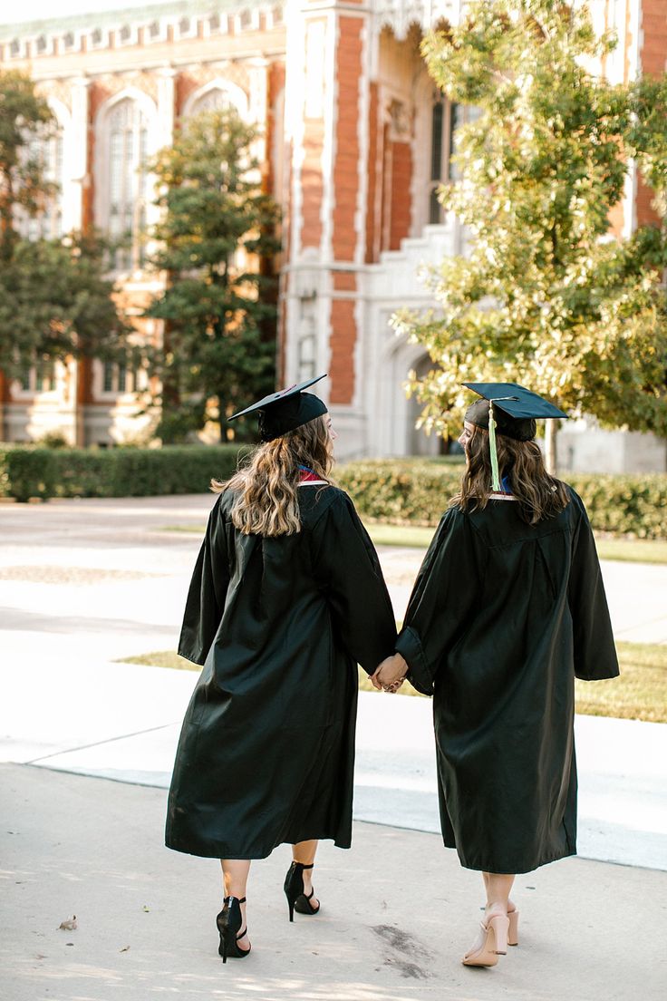 two women in graduation gowns holding hands