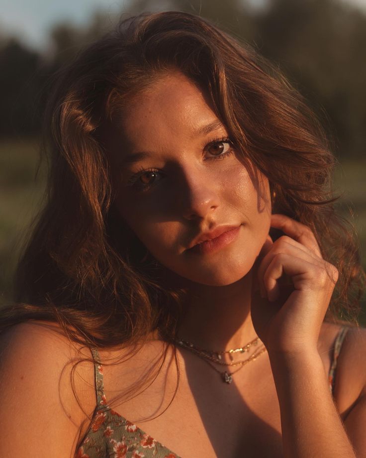 a beautiful young woman in a floral dress posing for the camera with her hand on her cheek