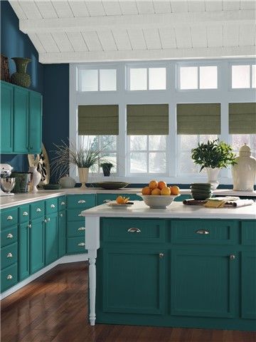 a kitchen with teal cabinets and white counter tops is pictured in this image, there are fruit on the island