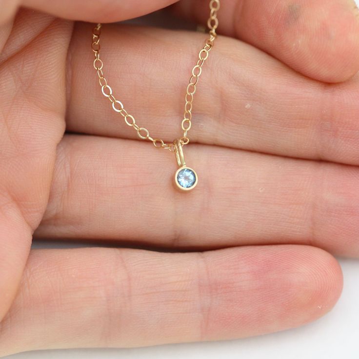 Very classy, simple, and dainty. This handcrafted gold pendant has a natural Blue Topaz stone and comes on your choice of a 16 or an 18 inch gold chain with the artist's tag attached to the clasp. It can also be paired with other pendants! Mix and match to create your own personalized necklace or mother necklace! Gold is 14ky. Stone measures 3mm in diameter. Birthstone for December. All Laine Benthall jewelry comes with a lifetime warranty. This pendant can also be purchased without the chain, j Delicate Blue Topaz Birthstone Jewelry, Yellow Gold Blue Topaz Jewelry Gift, Yellow Gold Blue Topaz Jewelry For Gifts, Blue Topaz Round Pendant Necklace Gift, Gift Blue Topaz Round Pendant Necklace, Gold Necklace With Blue Topaz Birthstone, Gold Blue Topaz Birthstone Necklace For Gift, Gold Blue Topaz Birthstone Necklace As Gift, Gold Birthstone Necklace With Blue Topaz For Gifts