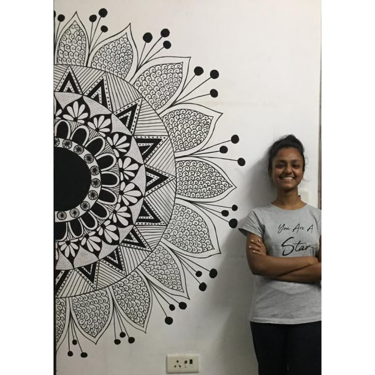 a woman standing next to a wall with a black and white design on it