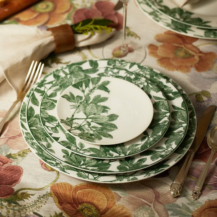 a table topped with plates and silverware on top of a floral covered table cloth