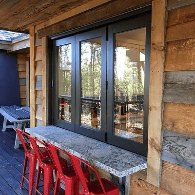 there are red chairs on the porch next to the table and bench in front of the door