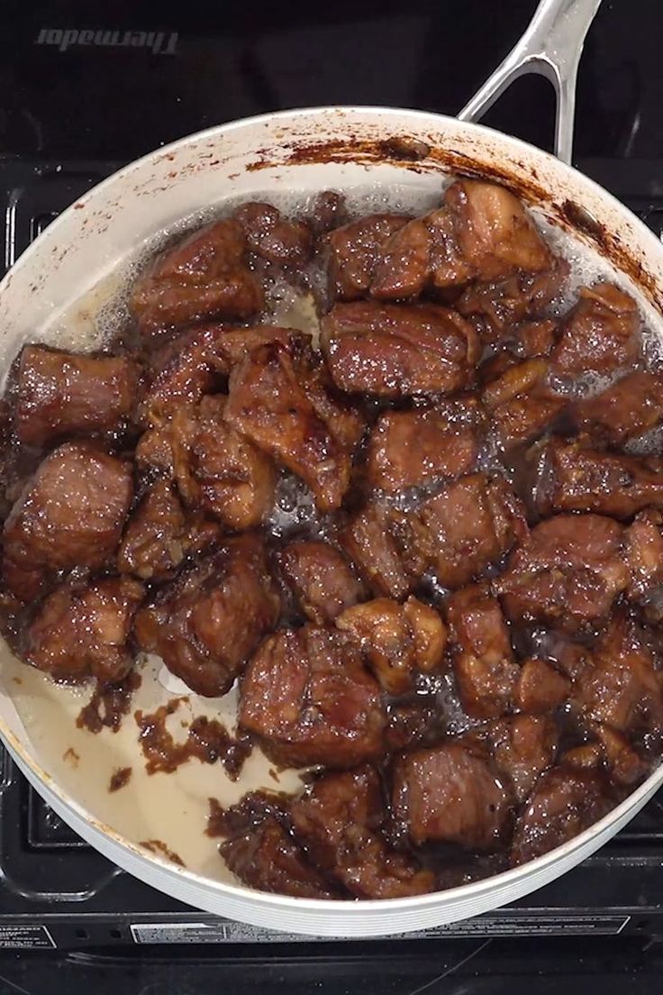 a pan filled with meat sitting on top of an oven