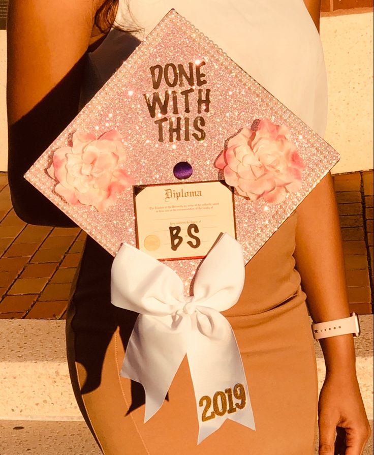 a woman holding up a graduation cap with flowers on it and the words, done with this