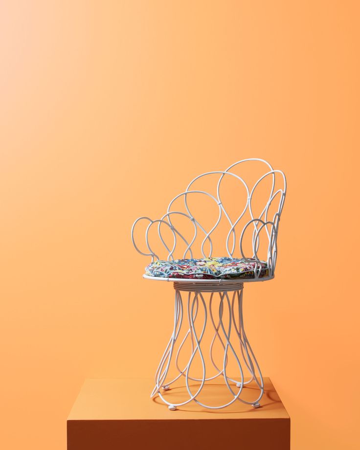 a white chair sitting on top of a wooden table next to an orange wall and floor