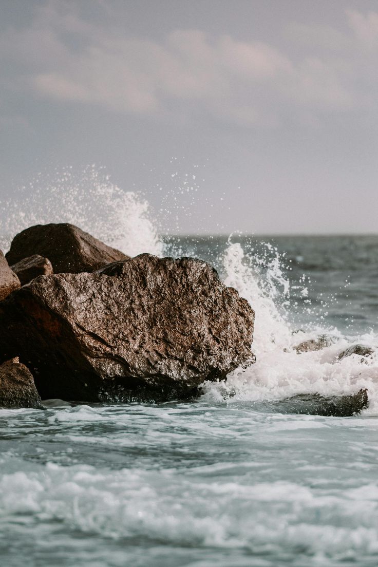 a person standing on top of a rock in the ocean