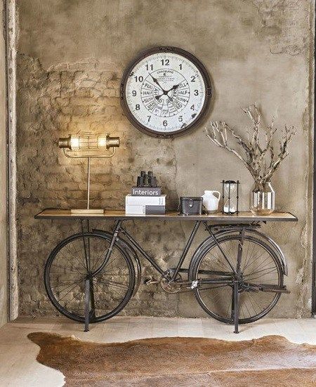 a bicycle is parked in front of a clock on the wall above it, next to a shelf with books and other items