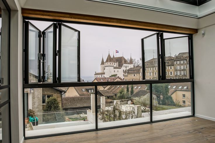 an open window shows the view of buildings and a castle in the distance, with a wooden floor