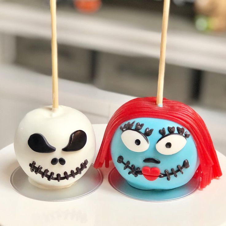 two cake pops decorated to look like jack skellings and the face of a girl with red hair