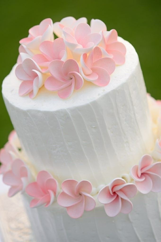 a three layer white cake with pink flowers on top