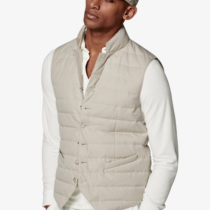 As an in-between layer or over a shirt, this sand padded vest is a versatile, trans-seasonal layering piece that effortlessly adds depth and casual appeal to any look. Casual Cotton Vest With Padded Collar, Beige Cotton Vest For Layering, Casual Business Vest For Spring, Casual Business Casual Vest For Spring, Beige Outerwear For Layering, Casual Winter Vest For Business Casual, Casual Business Winter Vest, Winter Business Casual Vest, Casual Fitted Cream Vest