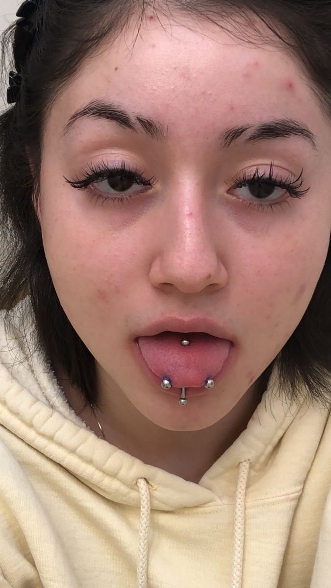 a young woman with piercings on her nose looking at the camera while wearing a hoodie