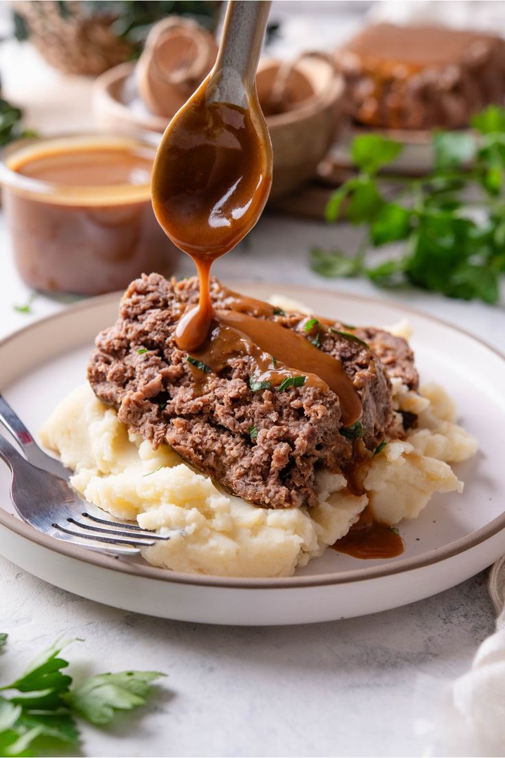 a spoon drizzling sauce over mashed potatoes