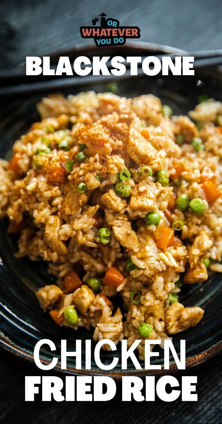 chicken fried rice with peas and carrots on a black plate