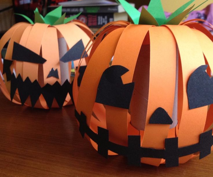 two paper pumpkins sitting on top of a wooden table