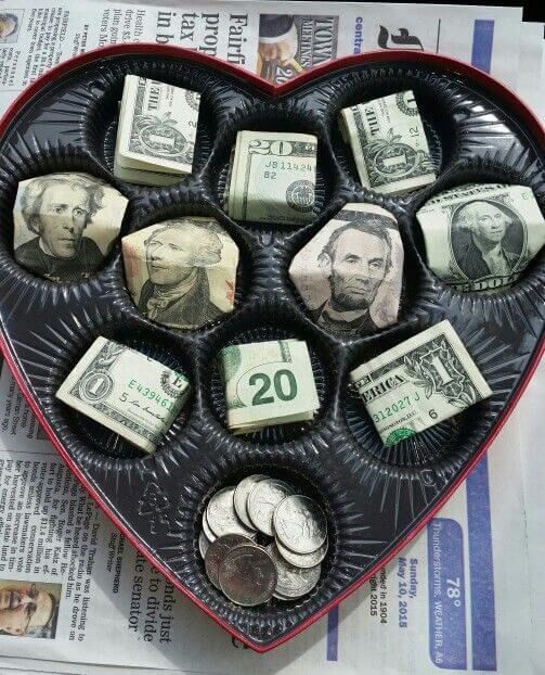 a heart shaped tray filled with money sitting on top of a newspaper