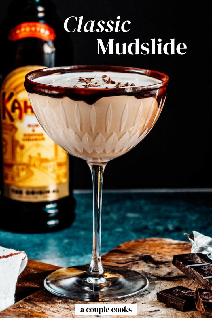 a close up of a drink in a coupe glass on a table with chocolate chunks