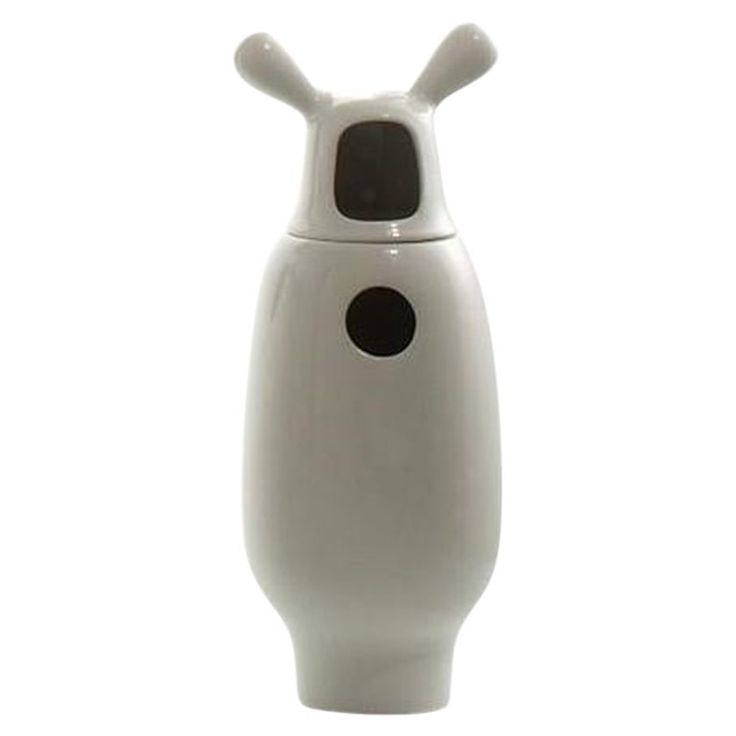 a white ceramic vase with black dots on the front and back of it's face