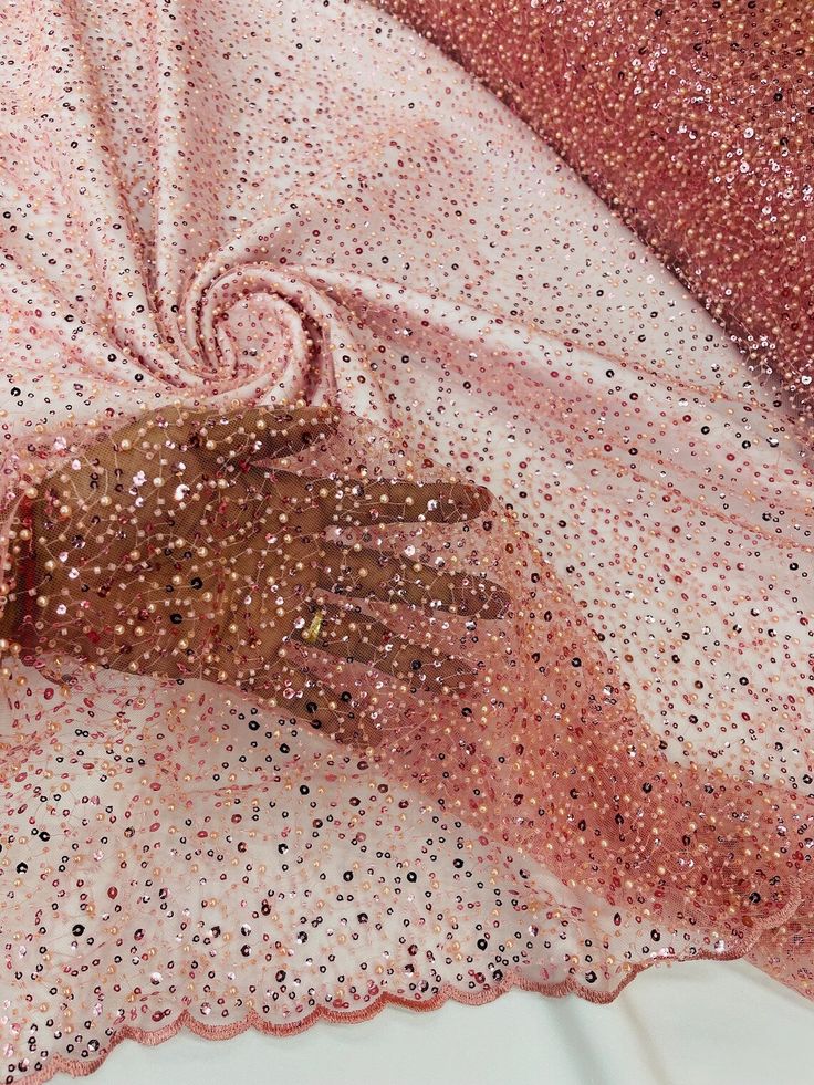 a pair of brown gloves sitting on top of a pink and white cloth covered in sequins