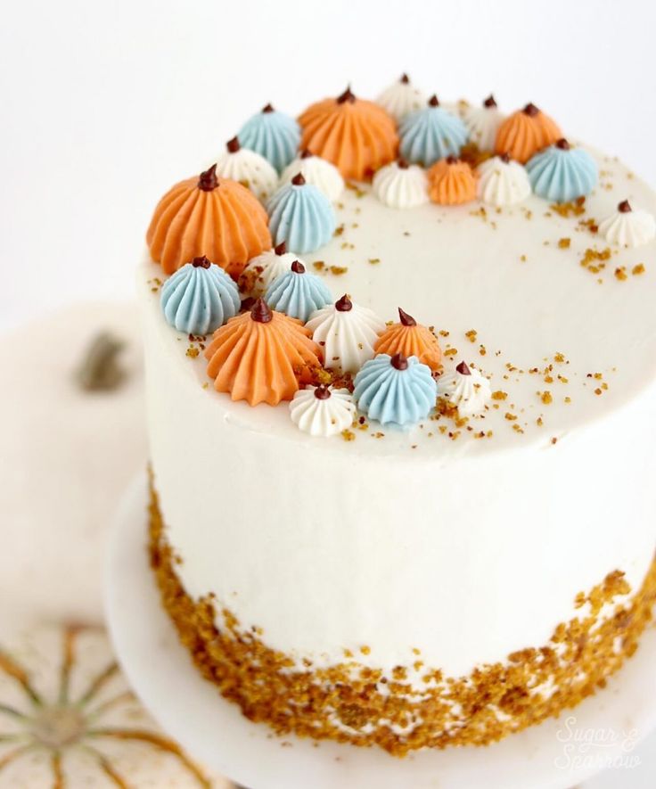 there is a white cake with orange and blue decorations on it