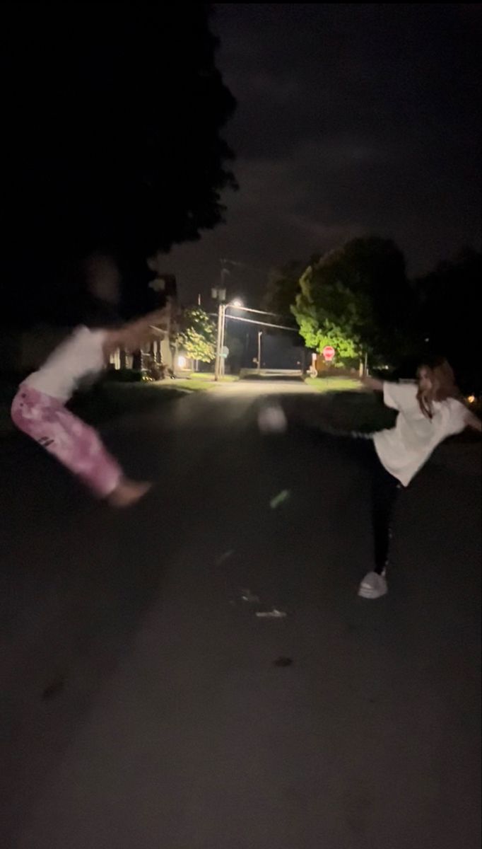 two people doing tricks in the street at night