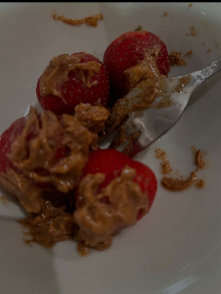 two strawberries are on a white plate with chocolate