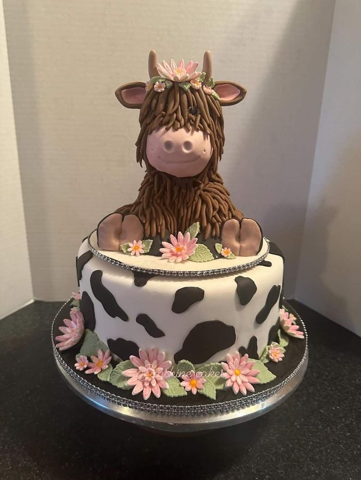 a decorated cake with a cow sitting on top of it