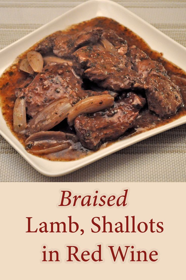 cooked lamb, shallots in red wine on a white plate with the words braised lamb, shallots in red wine