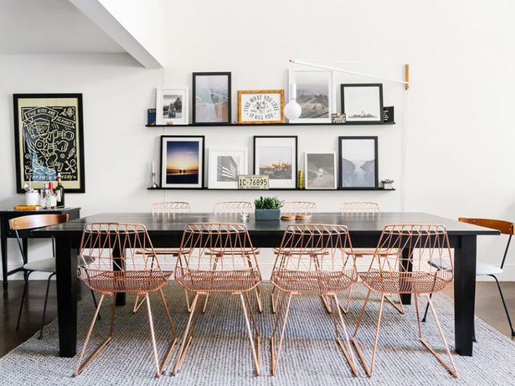 a dining room table with chairs and pictures on the wall above it in an apartment