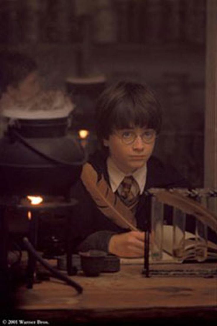 a young boy sitting at a table in front of an open fire place with candles