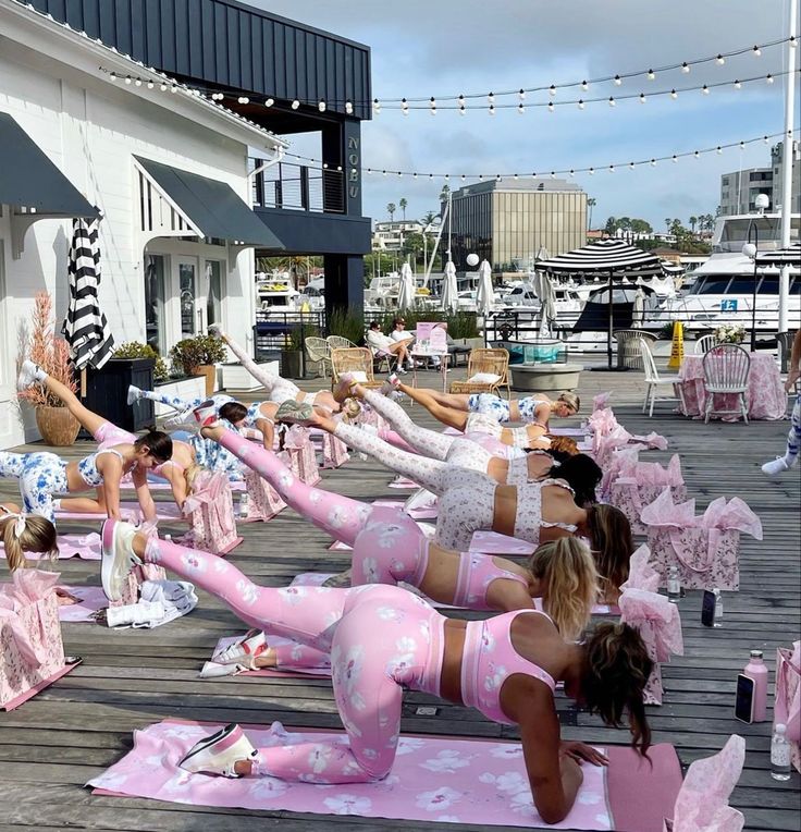 a group of women doing yoga on top of pink mats in front of a building