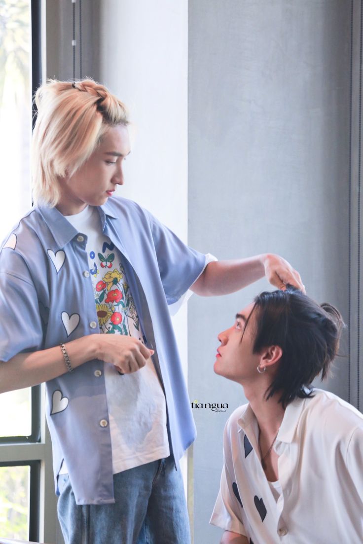 a man is getting his hair cut by another person in front of a window,