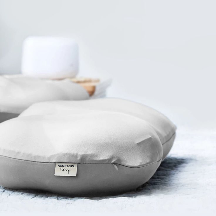 two pillows sitting on top of each other in front of a white wall and floor