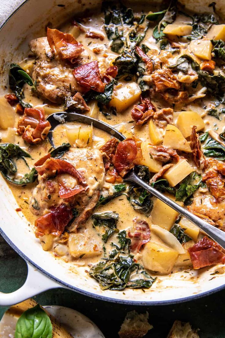 a skillet filled with spinach, potatoes and meat in a creamy white sauce