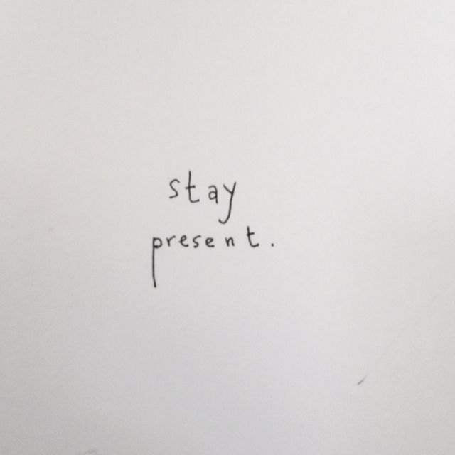 a white wall with writing on it that says, stay present it's written in cursive black ink