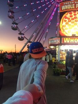 a person standing in front of a ferris wheel at night