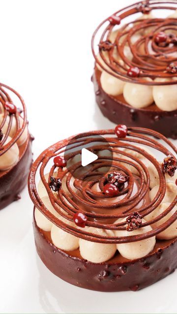 three chocolate desserts with white and red toppings on top, arranged in spiral designs