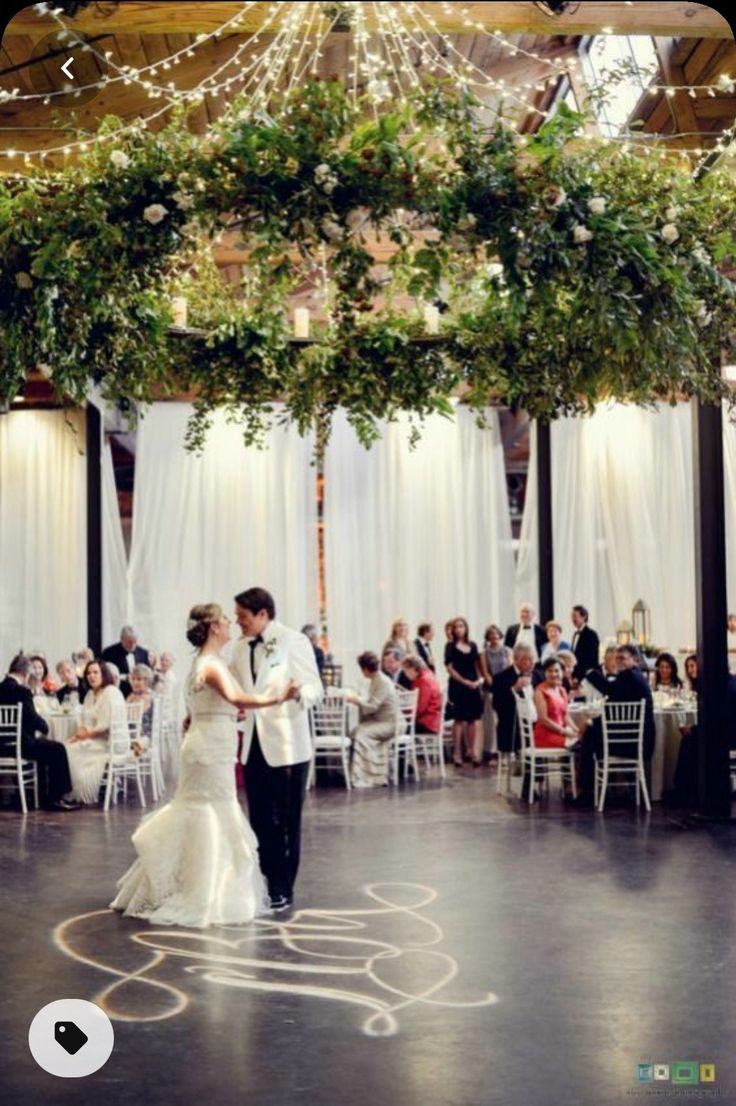 a bride and groom sharing their first dance at their wedding reception in front of an audience