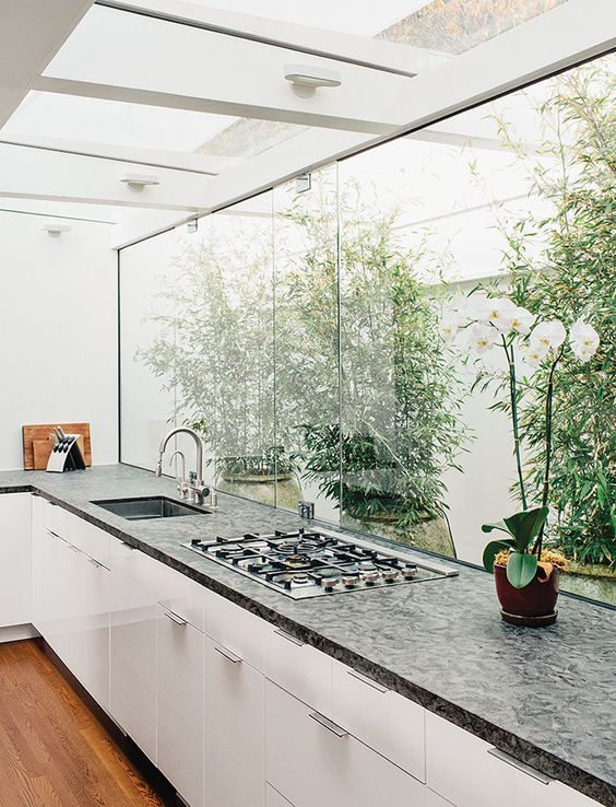 a kitchen with a stove top oven sitting next to a plant in a vase on the counter