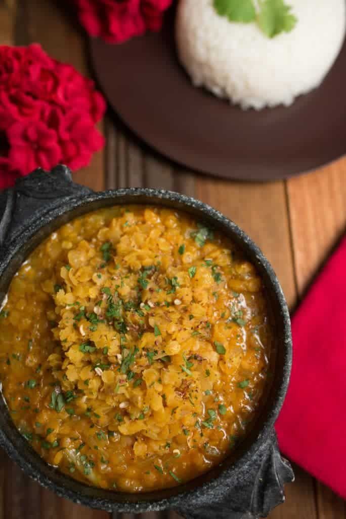 a close up of a bowl of food on a table with rice and flowers in the background