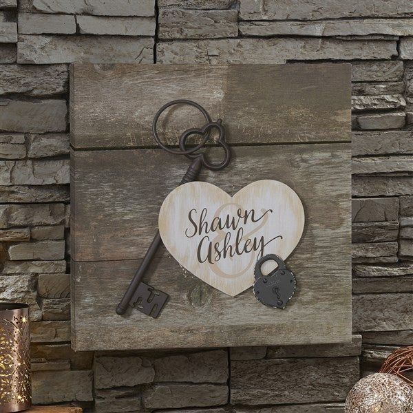 a wooden sign with a heart shaped key hanging from it's side on a brick wall