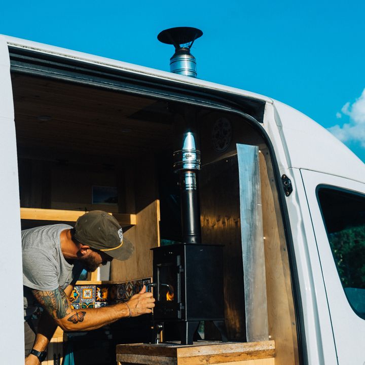 a man working on a stove in the back of a van