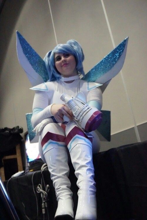 a woman dressed in white and blue sitting on top of a luggage bag with wings