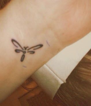 a woman's wrist tattoo with a dragonfly design on the left side of her arm