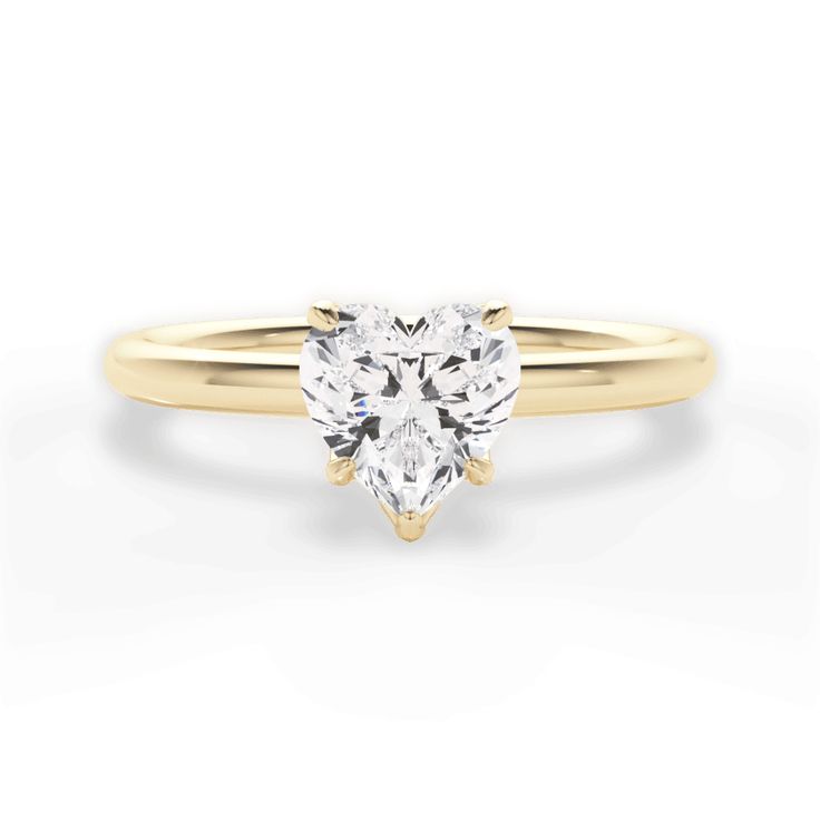 a heart shaped diamond engagement ring in yellow gold with a single stone on the side