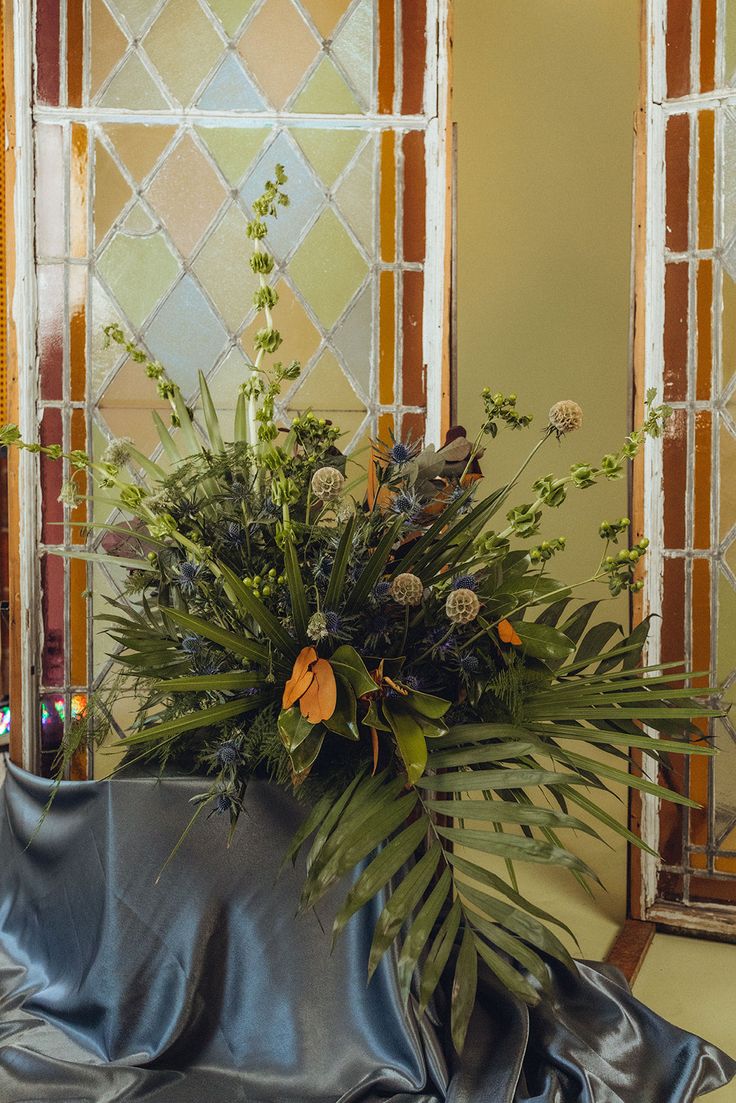 a vase filled with flowers sitting on top of a blue cloth covered table next to a mirror