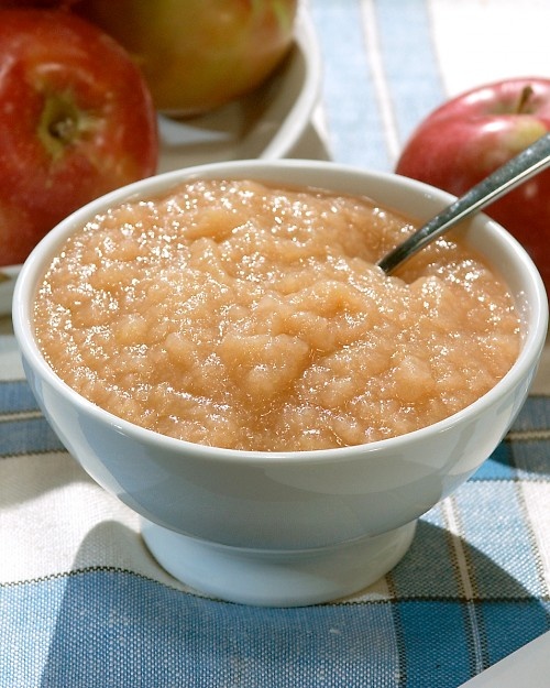 a bowl filled with oatmeal next to apples on a plaid table cloth