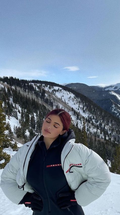 a woman standing on top of a snow covered slope